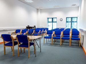 Office E with five rows of chairs facing a desk at the front.