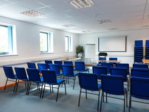 Office Q with three rows of chairs facing a projector screen.